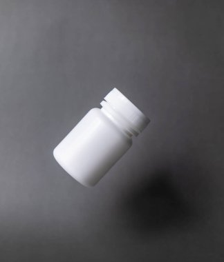 White plastic pill bottle, unlabelled, capped, floating on a black background.