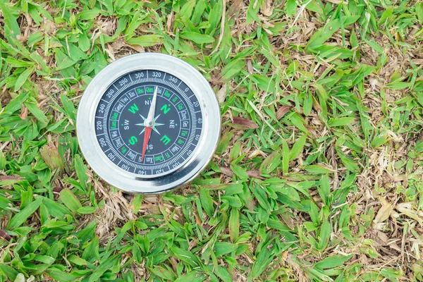 The compass is placed on the green grass showing north south  east west