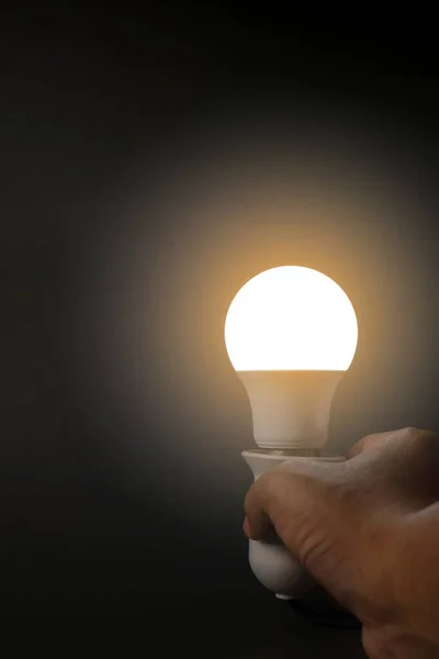 round led light bulb that illuminates a warm orange light on a black background, in the dark