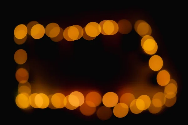 Take the light out of focus to create an oval, amber-colored bokeh in the darkness.