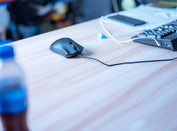 black focus mouse with long cable There are control buttons, pressing both left and right buttons work. On the work table, light brown wood grain. without mouse pad