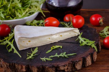 Brie peyniri ve marul yaprakları koyu ahşap arka planda