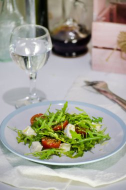 Beyaz tabakta roka, peynir ve vişneli domates salatası. Diyet sağlıklı yemek..