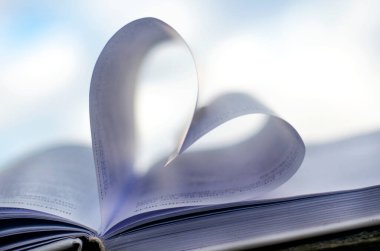 Kağıt bir kitabın sayfalarından çıkan kalp gökyüzüne karşı metin için yeri olan.