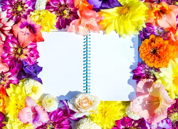 White space for text in the form of a notebook in a frame of bright summer flowers