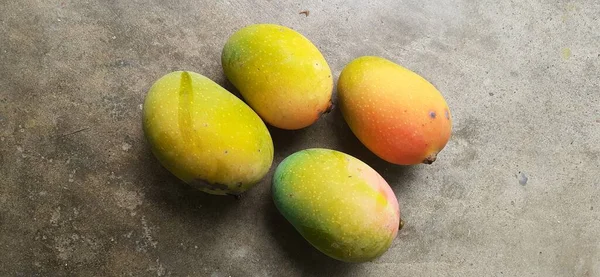 Olgun ve kırmızı mangolar yerde.