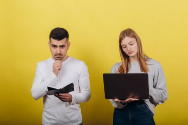 Erkek arkadaşı olan mutlu kız sarı arka planda dizüstü bilgisayara bakıyor. Birlikte okuyorlar. Sorunları çöz. Çalışma konsepti öğreniliyor