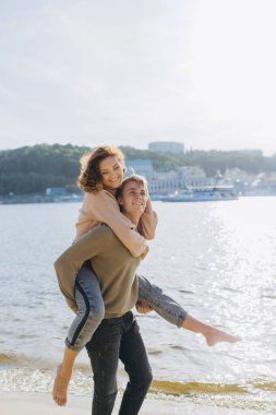 Kumsalda yürüyen mutlu genç çift. Yakışıklı bir adam kollarında bir kız taşıyor. Sevgi dolu bir çift eğleniyor. Gülüyorlar, sarılıyorlar.