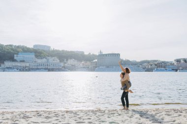 Kumsalda yürüyen mutlu genç çift. Yakışıklı bir adam kollarında bir kız taşıyor. Sevgi dolu bir çift eğleniyor. Gülüyorlar, sarılıyorlar. Toplam çerçeve. Metin için yer