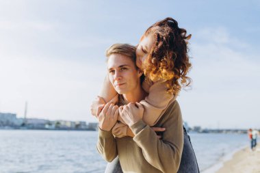 Kumsalda yürüyen mutlu genç çift. Yakışıklı bir adam kollarında bir kız taşıyor. Sevgi dolu bir çift eğleniyor. Gülüyorlar, sarılıyorlar.