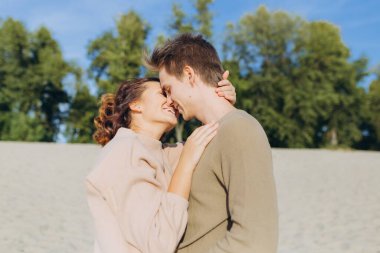 Birbirine aşık bir çiftin portresi. Mutlu romantik genç çift günbatımının tadını çıkarıyor. Adam kıza sarılıyor ve onu dudaklarından öpüyor.