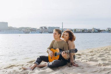 Aşık mutlu bir çift. Genç bir çiftin çarpıcı şehvetli portresi. Genç adam sevgili kızı için gitar çalıyor..