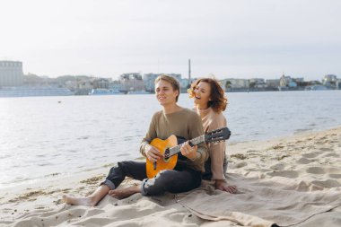 Aşık mutlu bir çift. Genç bir çiftin çarpıcı şehvetli portresi. Genç adam sevgili kızı için gitar çalıyor..