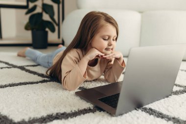 Laptop ekranına bakan şirin bir bebek. Evdeki kanepede uzanmış interneti kullanan küçük bir kız. Teknolojiye ya da bilgisayara bağımlılık. Çevrimiçi eğitim.