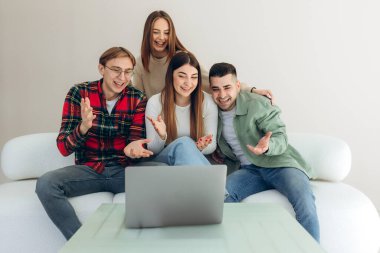 Bir grup arkadaş odada otururken dizüstü bilgisayarda bir şeye bakıp gülüyorlar.