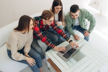 Bir grup arkadaş dizüstü bilgisayardan bir şeye bakıyor.