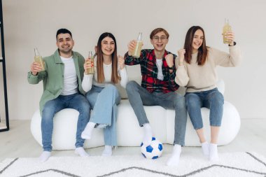 Mutlu arkadaşlar ya da futbol taraftarları televizyonda maç izleyip zaferi evde kutluyorlar. Dostluk, spor ve eğlence kavramı.