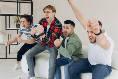 Bir grup arkadaş televizyonda maç izleyip golü kutluyorlar.