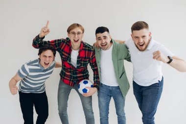 İşte bu! Kazananlar! Dört neşeli genç adam ayakta dikiliyor ve sıradan kıyafetler ve kotlarla saf arka planda zafer için işaret veriyorlar. Onlar spor oyunlarının hayranları.