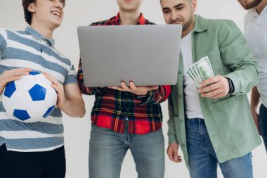 Bir grup erkek arkadaş dizüstü bilgisayardan spor bahis kuponlarına bakıyor. Hangi takıma oynayacağına karar ver. Kumar konsepti. Spor bahisleri. Online bahis