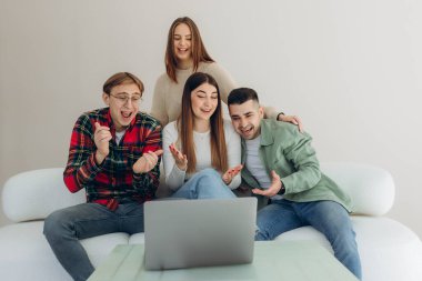 Kanepede oturup internetten video izleyen ya da dizüstü bilgisayardaki sosyal ağ uygulamasını kullanan bir grup arkadaş.