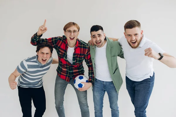 İşte bu! Kazananlar! Dört neşeli genç adam ayakta dikiliyor ve sıradan kıyafetler ve kotlarla saf arka planda zafer için işaret veriyorlar. Onlar spor oyunlarının hayranları.