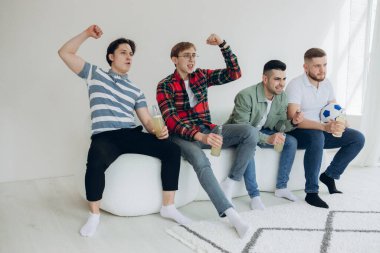 Bir grup arkadaş televizyonda maç izleyip golü kutluyorlar.