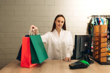 Giyim mağazasında satıcı müşteriye çanta veriyor.