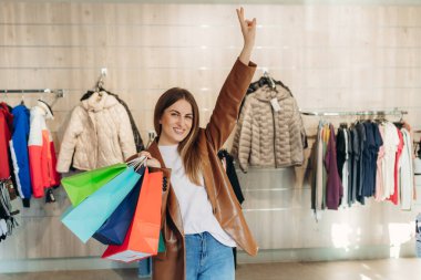 Giyim mağazasında alışveriş torbaları tutan mutlu genç bir kadın. Alışveriş konsepti. Satılık.