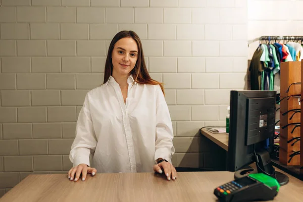 Female small business owner standing behind checkout counter