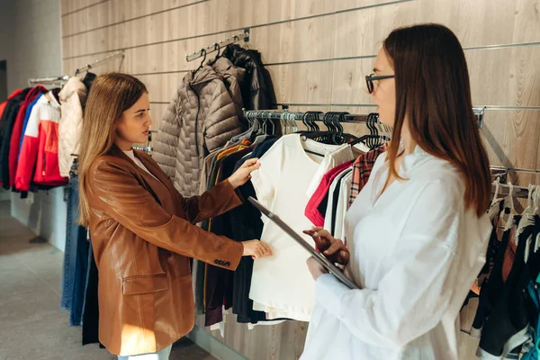Profesyonel Alışveriş Asistanı Dijital Tablet Kullanarak Kadın Müşterinin Kıyafet Almasına ve Kişisel Stili Geliştirmesine Yardım Ediyor. Boş Alan