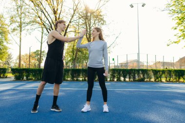 Spor kıyafetlerinde gülümseyen arkadaşlar stadyumda beşlik çakıyor.