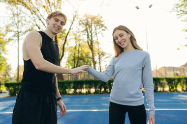 Genç adam ve kız stadyumda spor yapmaya başlamadan önce birbirlerini selamlıyorlar.