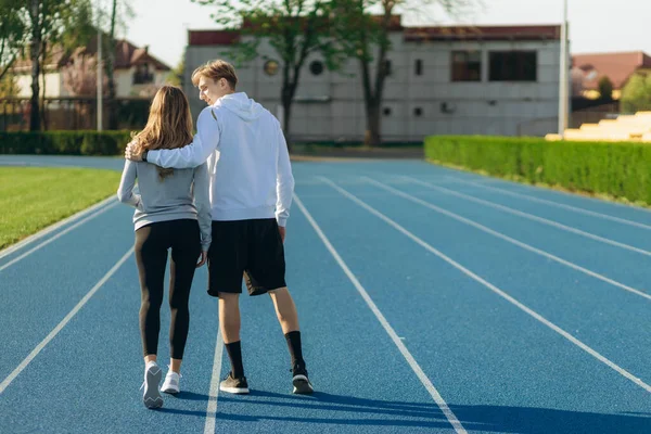 Sabahleyin stadyumda koşan bir çiftin arkasından manzara. Çalışma Çalışıyor