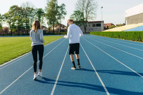 Sabahleyin stadyumda koşan bir çiftin arkasından manzara. Çalışma Çalışıyor