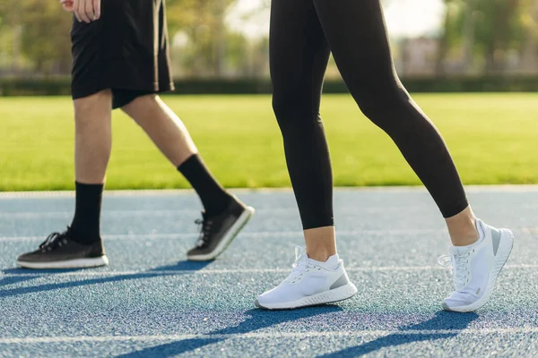 Şafakta koşucuların bacakları. Stadyumda koşu. Eğitim sporcuları.
