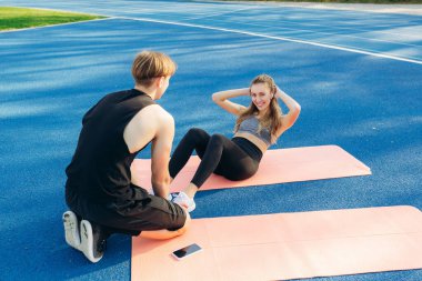 Yan görünüm gülümseyen bir erkek yardımıyla mindere basın egzersizleri yapıyor bir kız. Mutlu bir adam ve kadın egzersizleri yapıyor keyifli bir yolculuk şekil.
