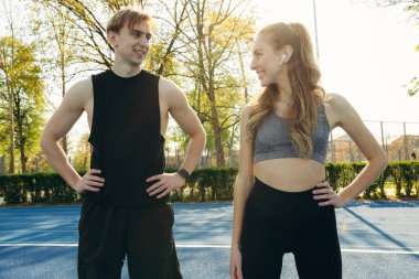 Spor kıyafetleri içinde genç bir çiftin portresi açık havada spor, spor ve sağlıklı bir yaşam tarzı yapıyor.