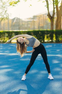 Stadyumun dışında duran ve güneşli bir günde ısınan bir sporcu..