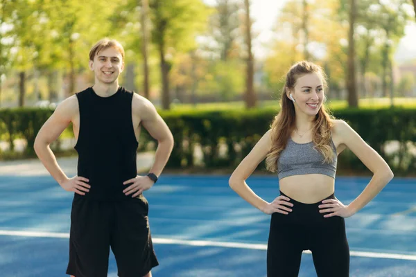 Spor kıyafetleri içinde genç bir çiftin portresi açık havada spor, spor ve sağlıklı bir yaşam tarzı yapıyor.