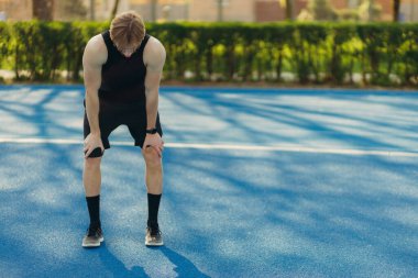 Koşu üstüne koşu yapmaktan yorgun bir sporcu. Antrenmandan sonra dinlenen bir adam.