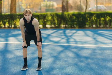 Koşu üstüne koşu yapmaktan yorgun bir sporcu. Antrenmandan sonra dinlenen bir adam.