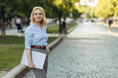 Portrait of a mature businesswoman holding a laptop. Happy senior woman office worker. Women of the 50s. The concept of work. Freelance. Success