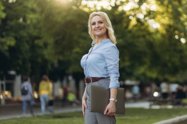 Portrait of a mature businesswoman holding a laptop. Happy senior woman office worker. Women of the 50s. The concept of work. Freelance. Success