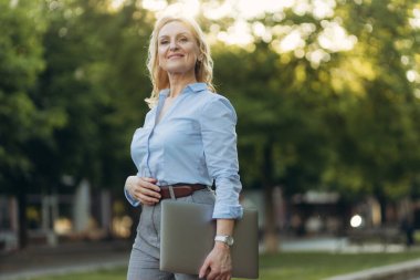 Portrait of a mature businesswoman holding a laptop. Happy senior woman office worker. Women of the 50s. The concept of work. Freelance. Success