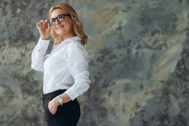 Duvarda gülümseyen gözlüklü mutlu olgun bir kadın. Kadın 50 'li yaşlarda. Mesaj için yer. Pankart
