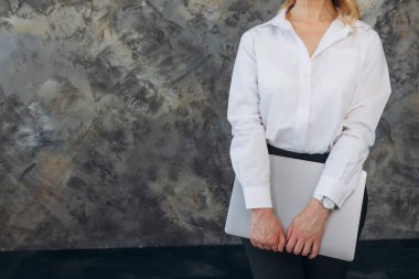 Kapalı bir dizüstü bilgisayarın 50 yaşındaki bir kadının ellerinde yakın plan görüntüsü.