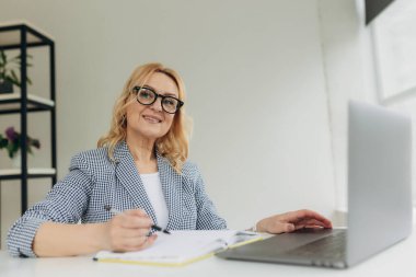 İş yerinde dizüstü bilgisayarında çalışan çekici bir iş kadını portresi.
