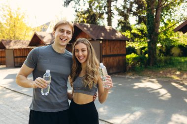Eğitimden sonra parkta dinlenen ve su içen çift. Sağlıklı yaşam tarzı kavramı