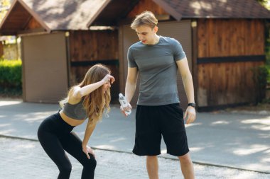 Eğitimden sonra parkta dinlenen ve su içen çift. Sağlıklı yaşam tarzı kavramı